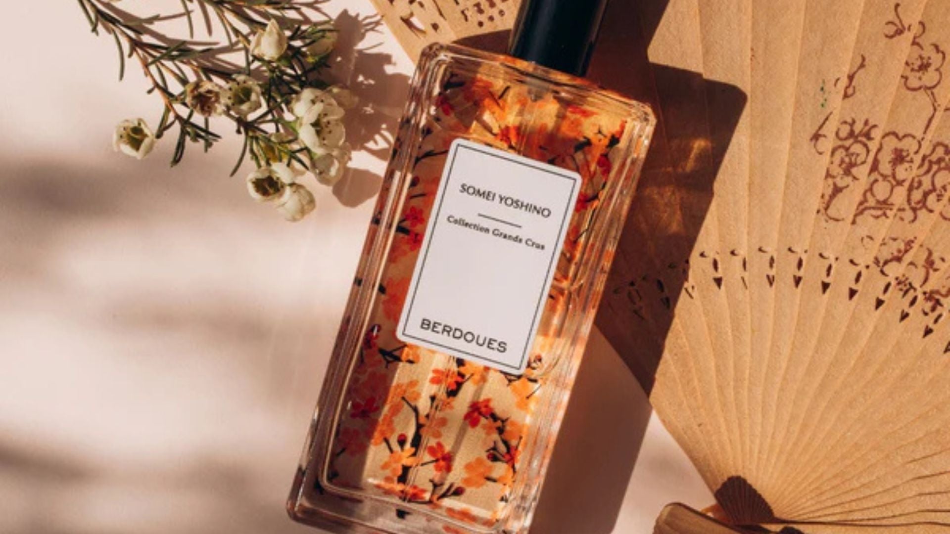Flacon de parfum Somei Yoshino de la collection Grands Crus de Berdoues, accompagné de fleurs blanches et d’un éventail, illustrant l’élégance et la personnalité olfactive.